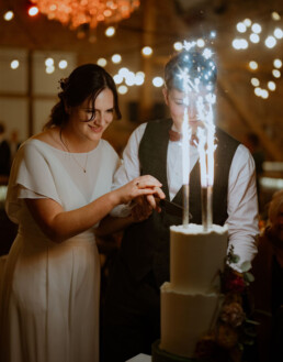 The is a picture of a couple who just got married. They are cutting a wedding cake with fireworks on it. This picture was taken by Simon Leclercq a Belgian wedding photographer. This picutre was taken in Het Goed van Gothem a wedding venue close to Hasselt in Belgium Simon Leclercq fotograaf trouwfotograaf Leuven België Belgium Louvain photography destination wedding photography op locatie